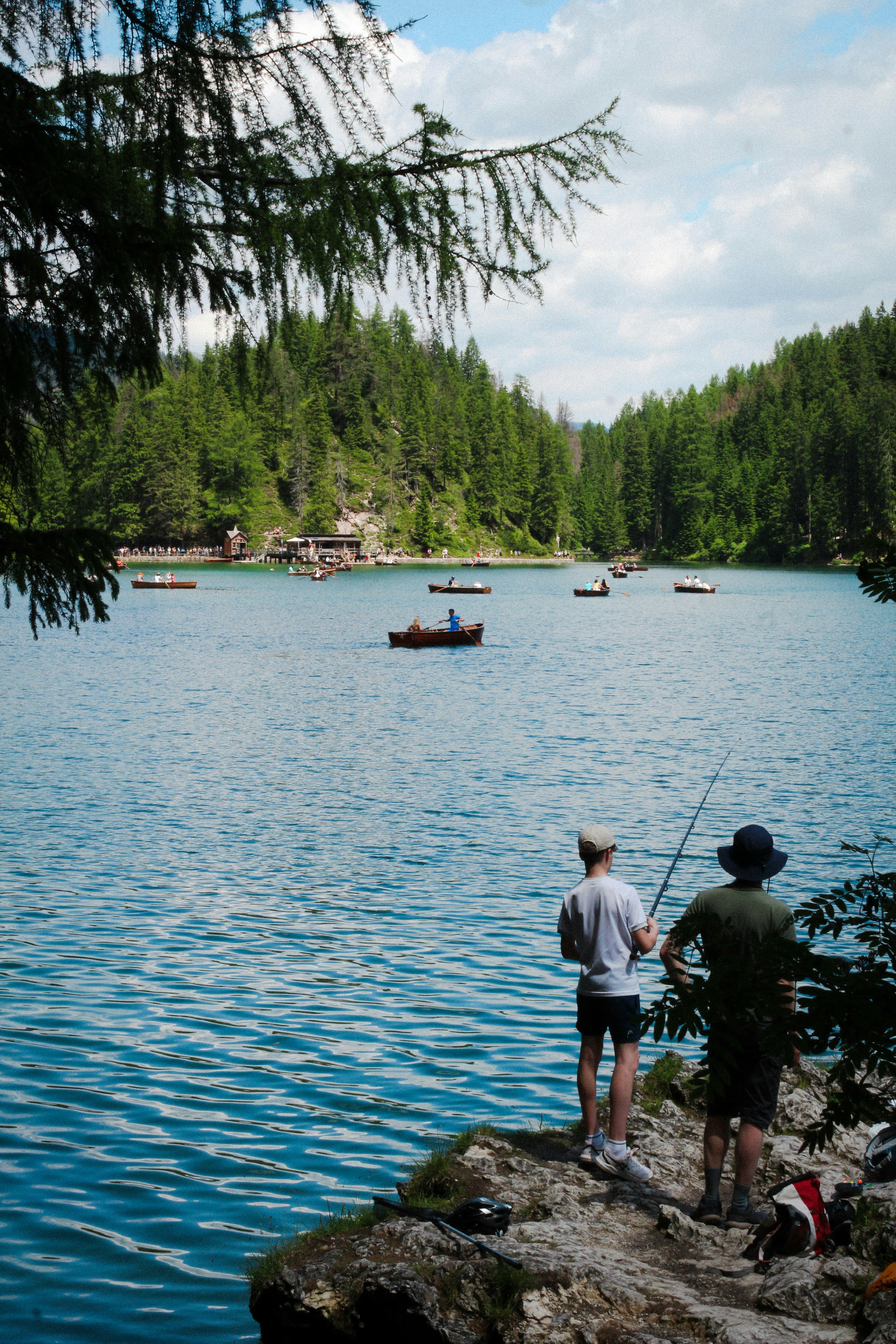 A couple of men standing on top of a rock next to a body of water