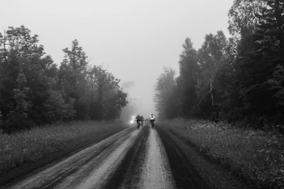 A black and white photo of two people walking down a road
