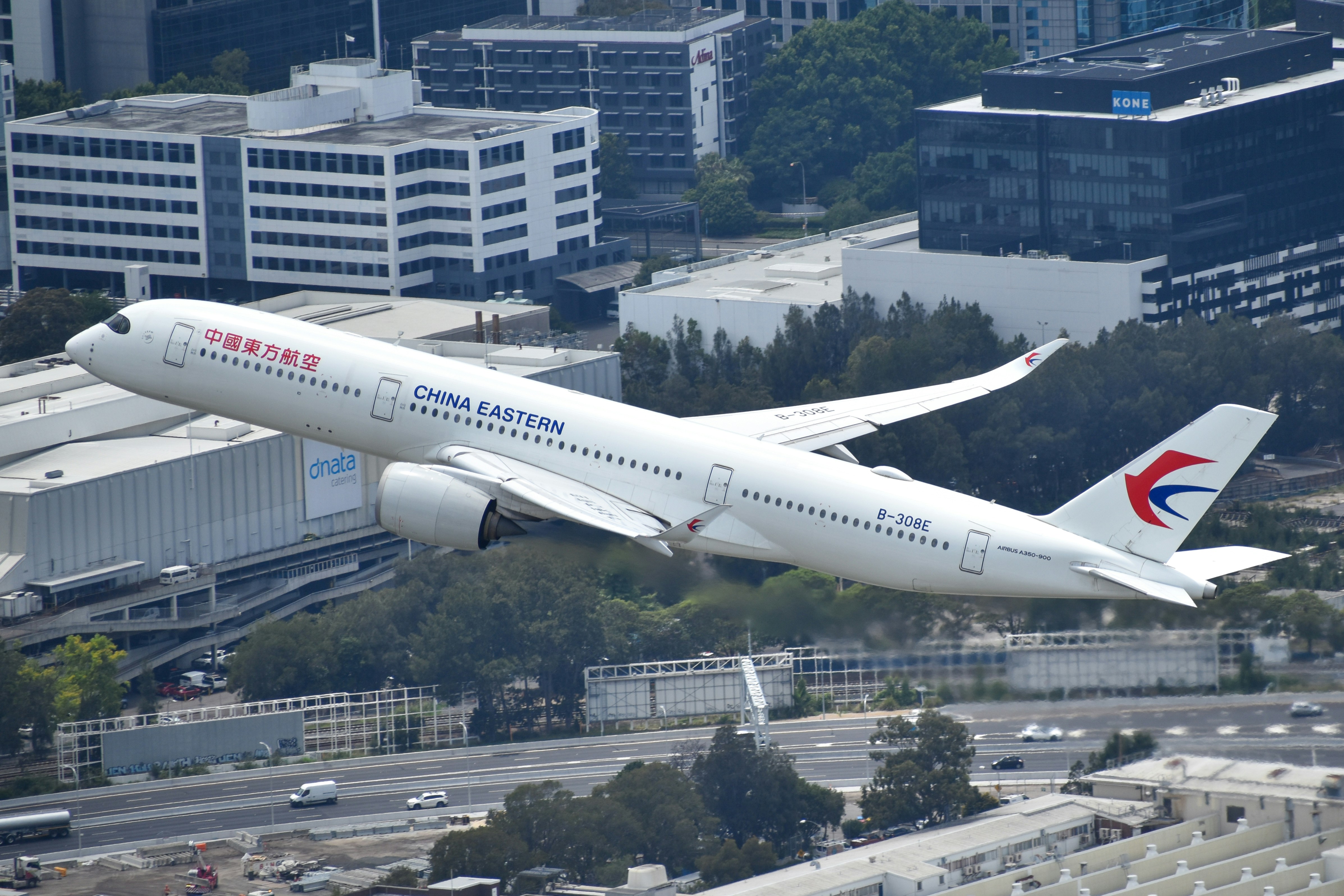 A large passenger jet flying over a city, China Eastern A350 departing Sydney Airport