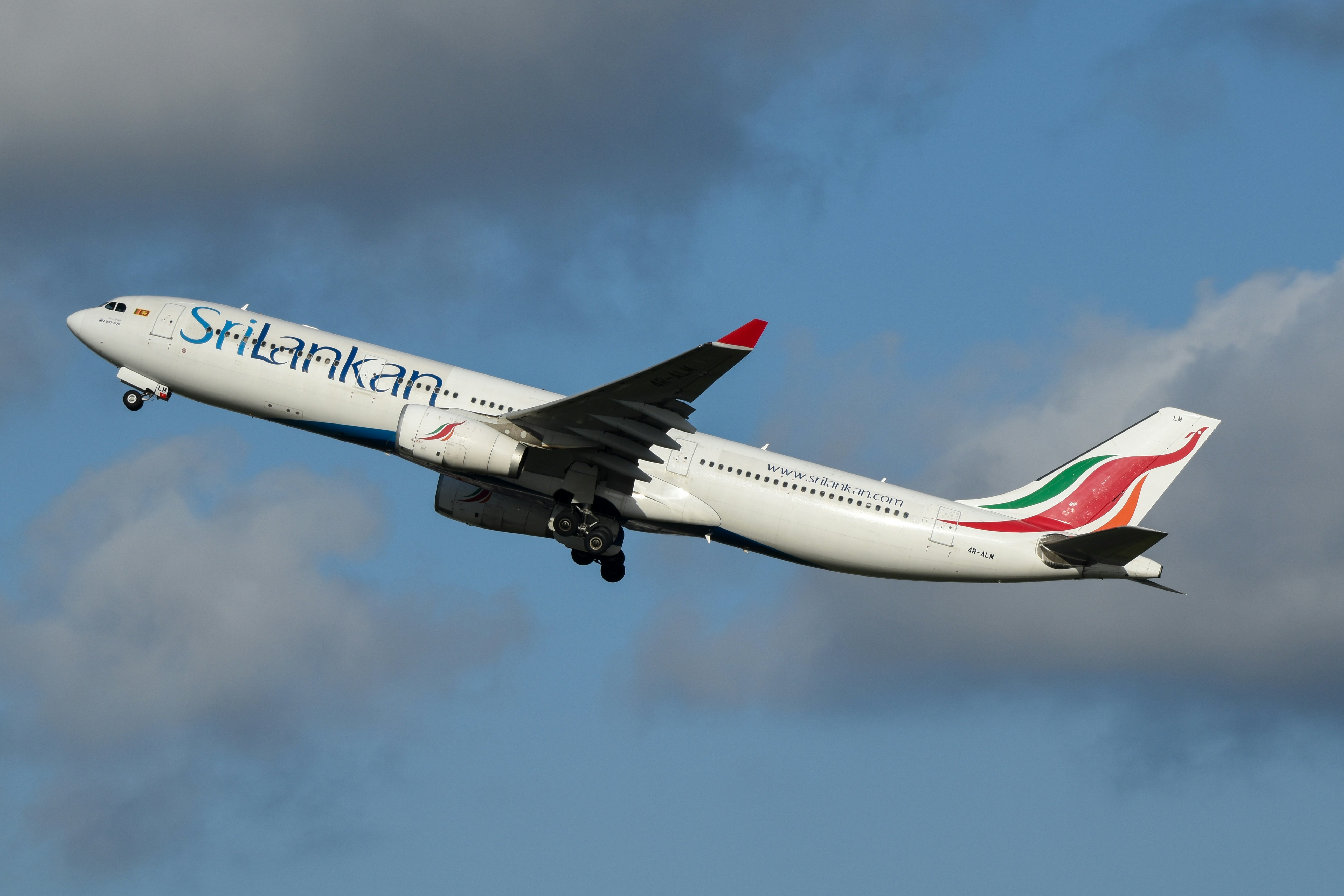A large jetliner flying through a cloudy blue sky, SriLankan Airlines A330 departing Sydney