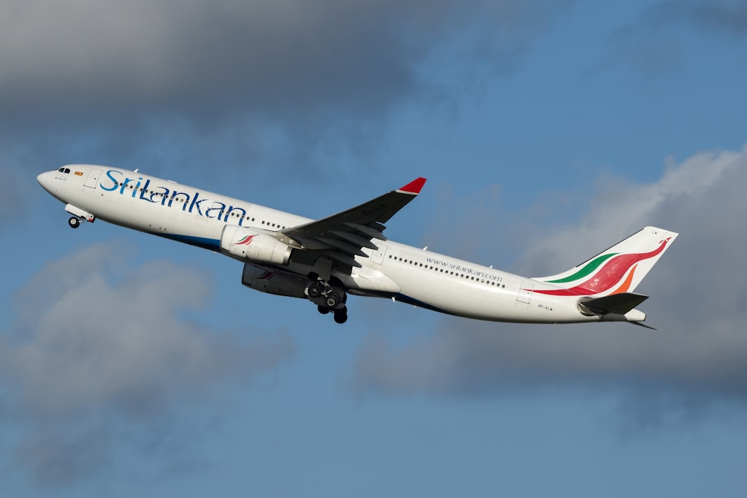 A large jetliner flying through a cloudy blue sky, SriLankan Airlines A330 departing Sydney