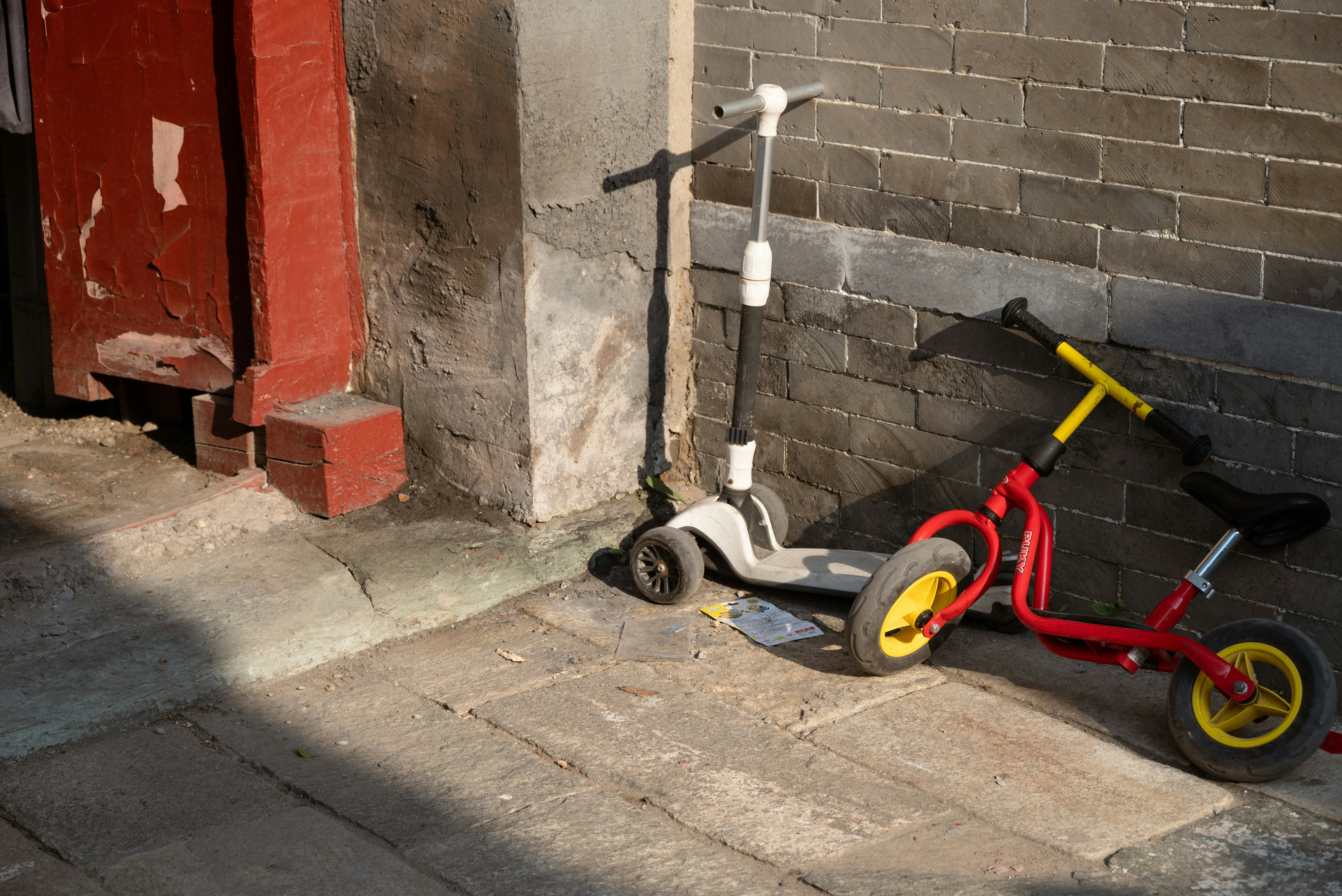 A red scooter parked next to a brick building
