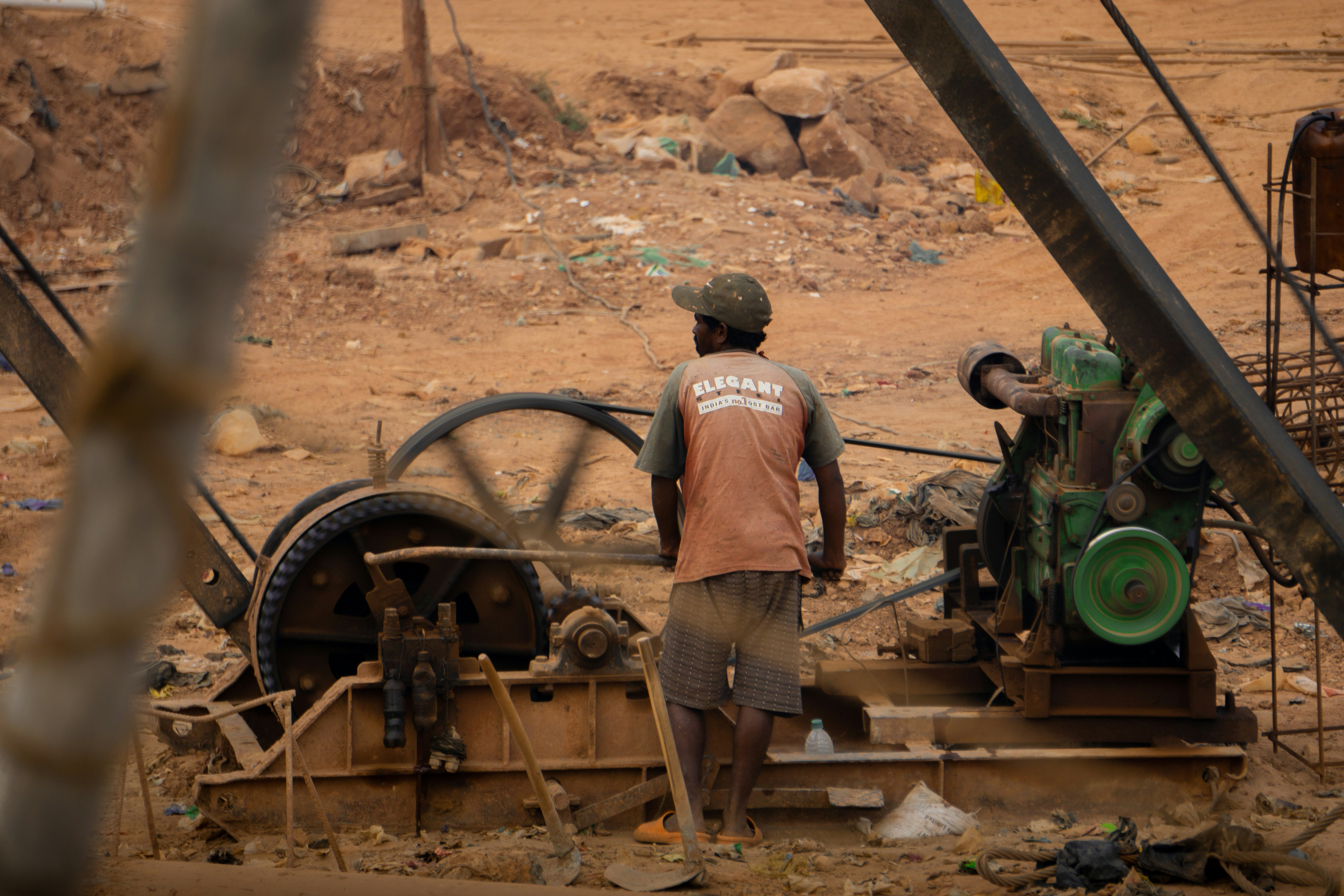 A man standing next to a machine in a dirt field