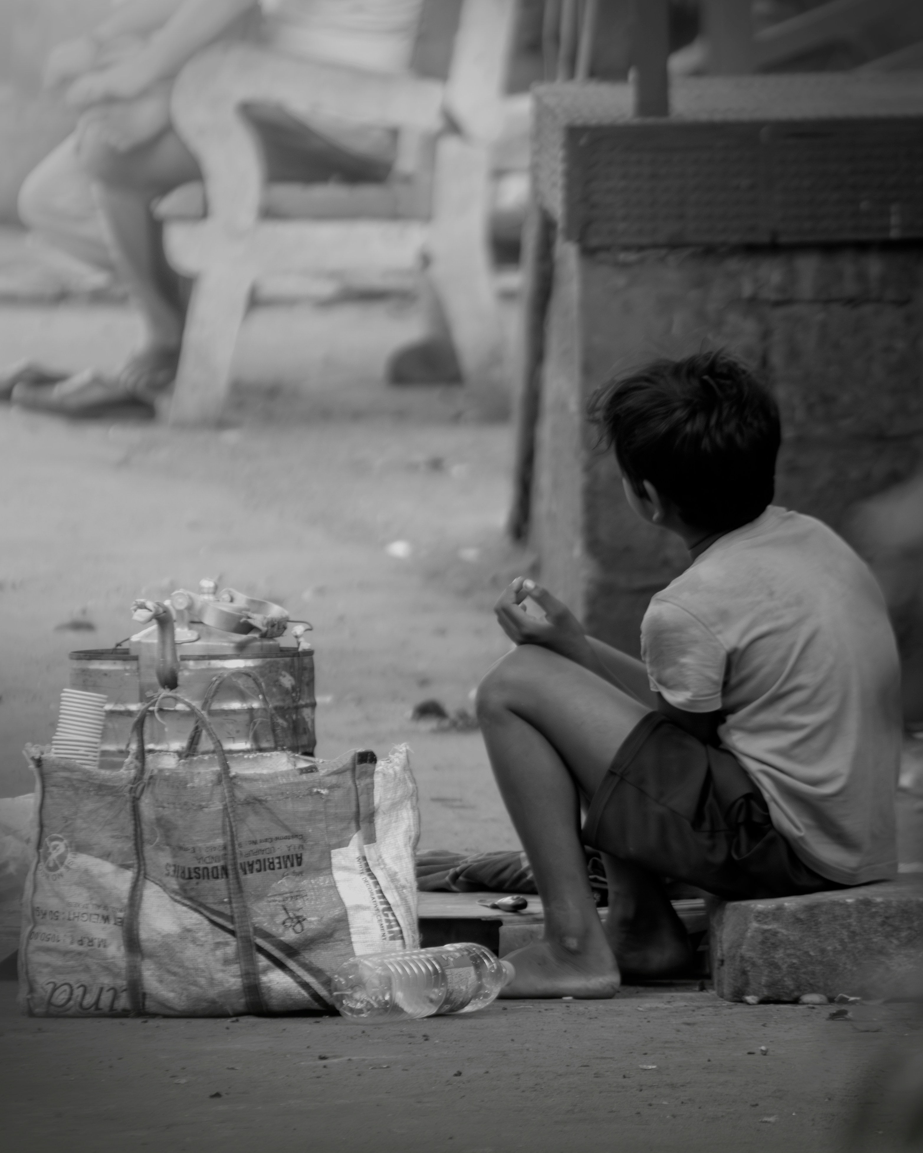A boy sitting on the ground next to a bag