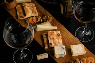 A wooden table topped with wine glasses and cheese