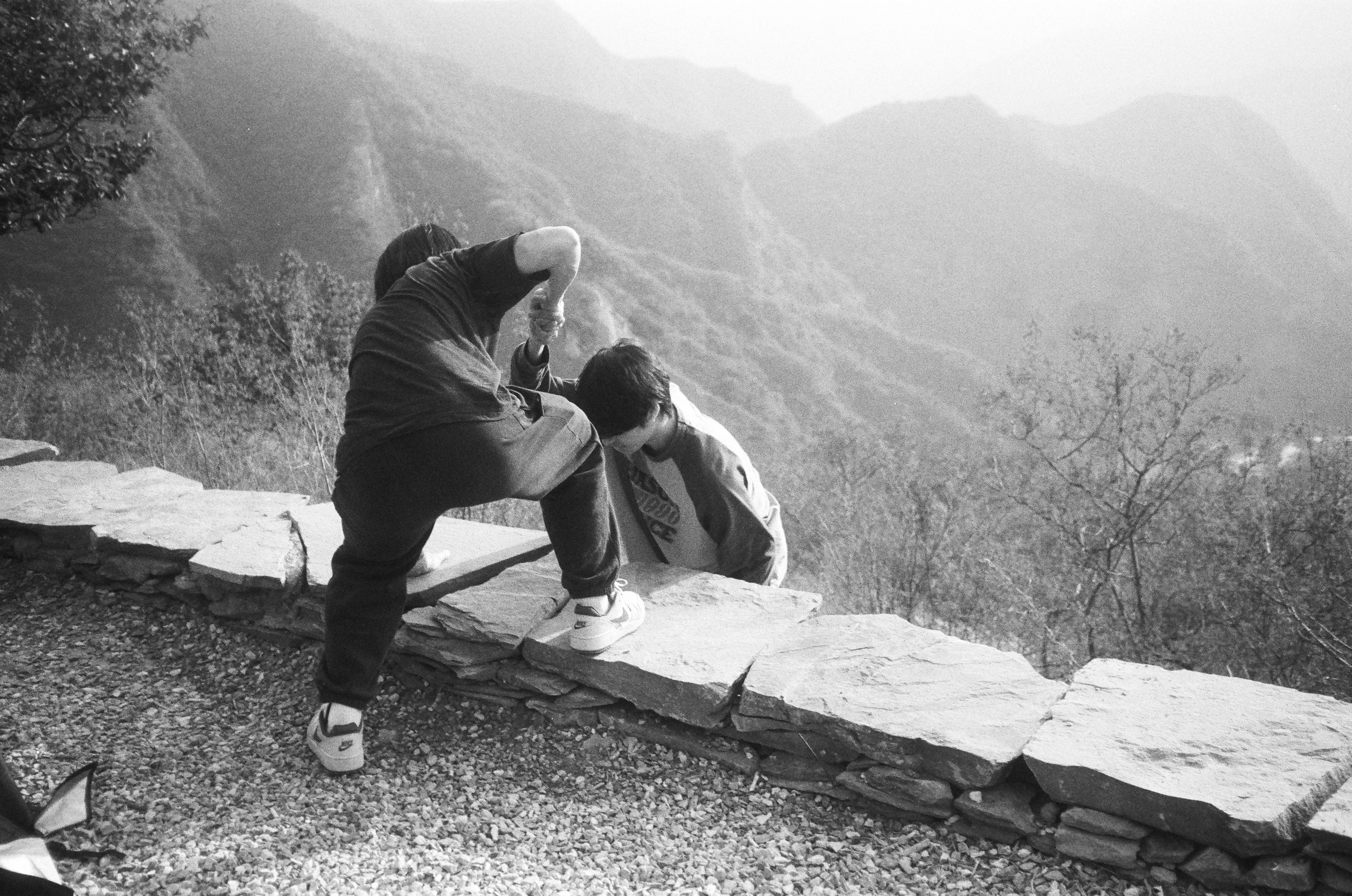 A poignant photo of a young child being embraced by his emotional parents, with a faint backdrop of mountains, symbolizing reunion after a difficult journey.
