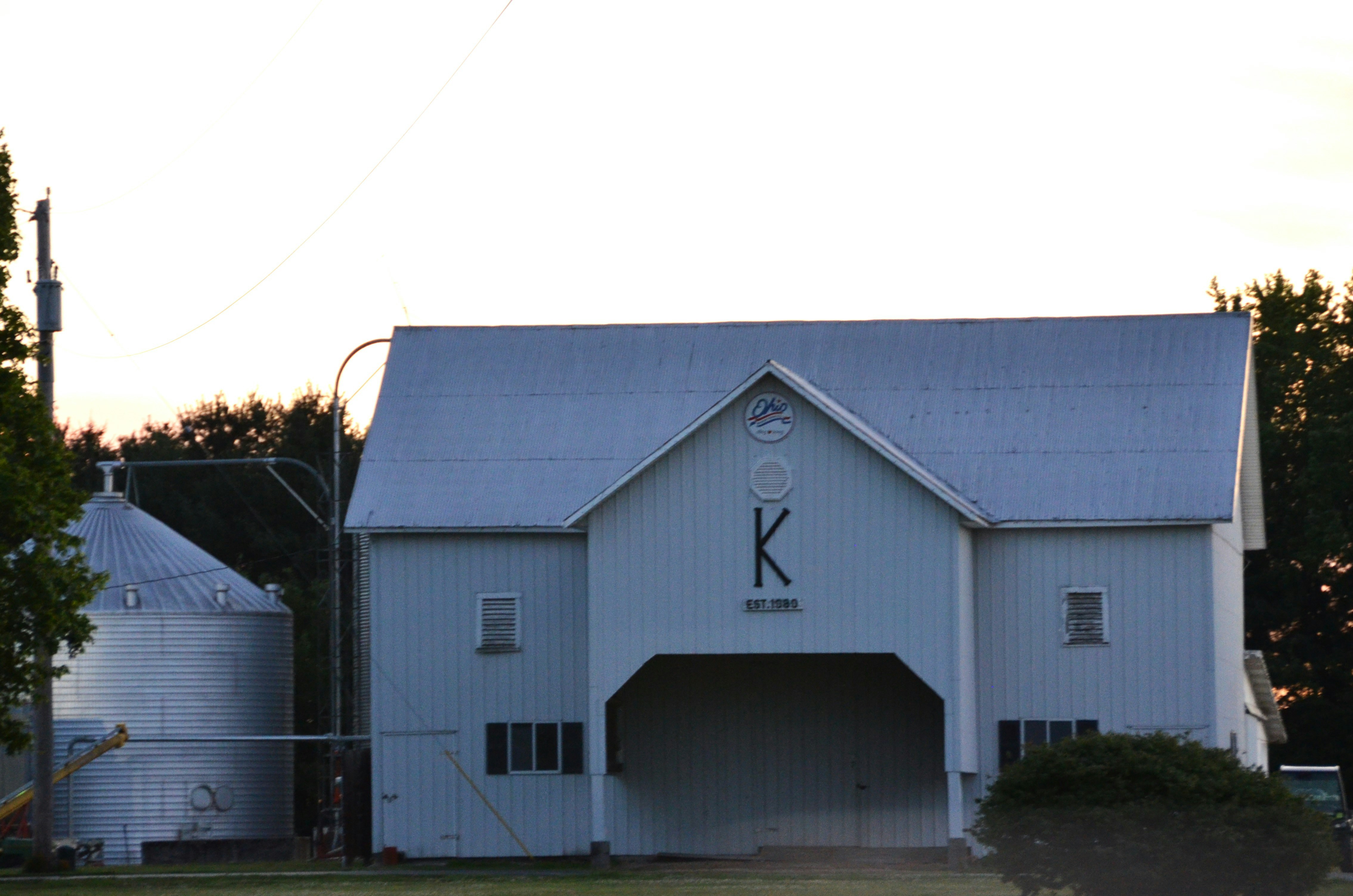 A large white barn with a clock on the side of it
