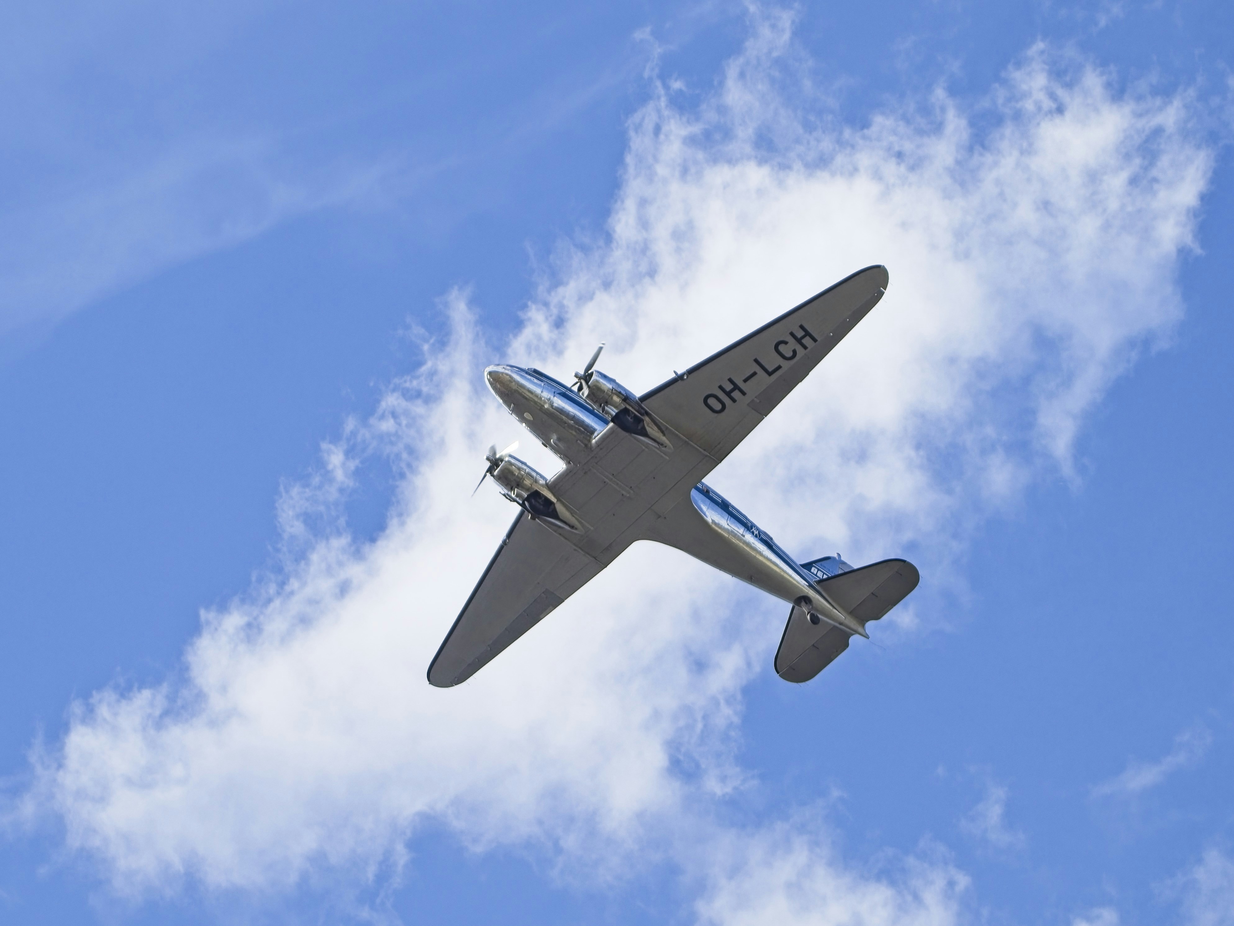 A small plane flying through a blue sky, DC-3 flying over