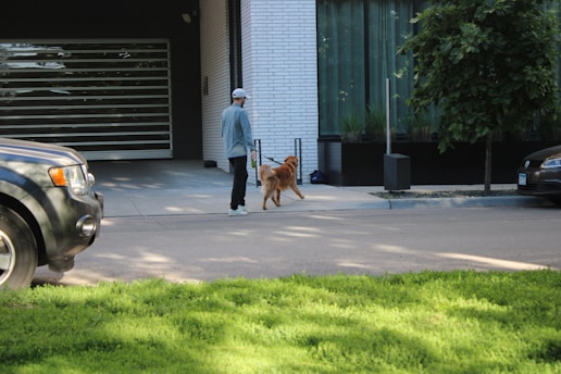 A man walking a dog in front of a garage