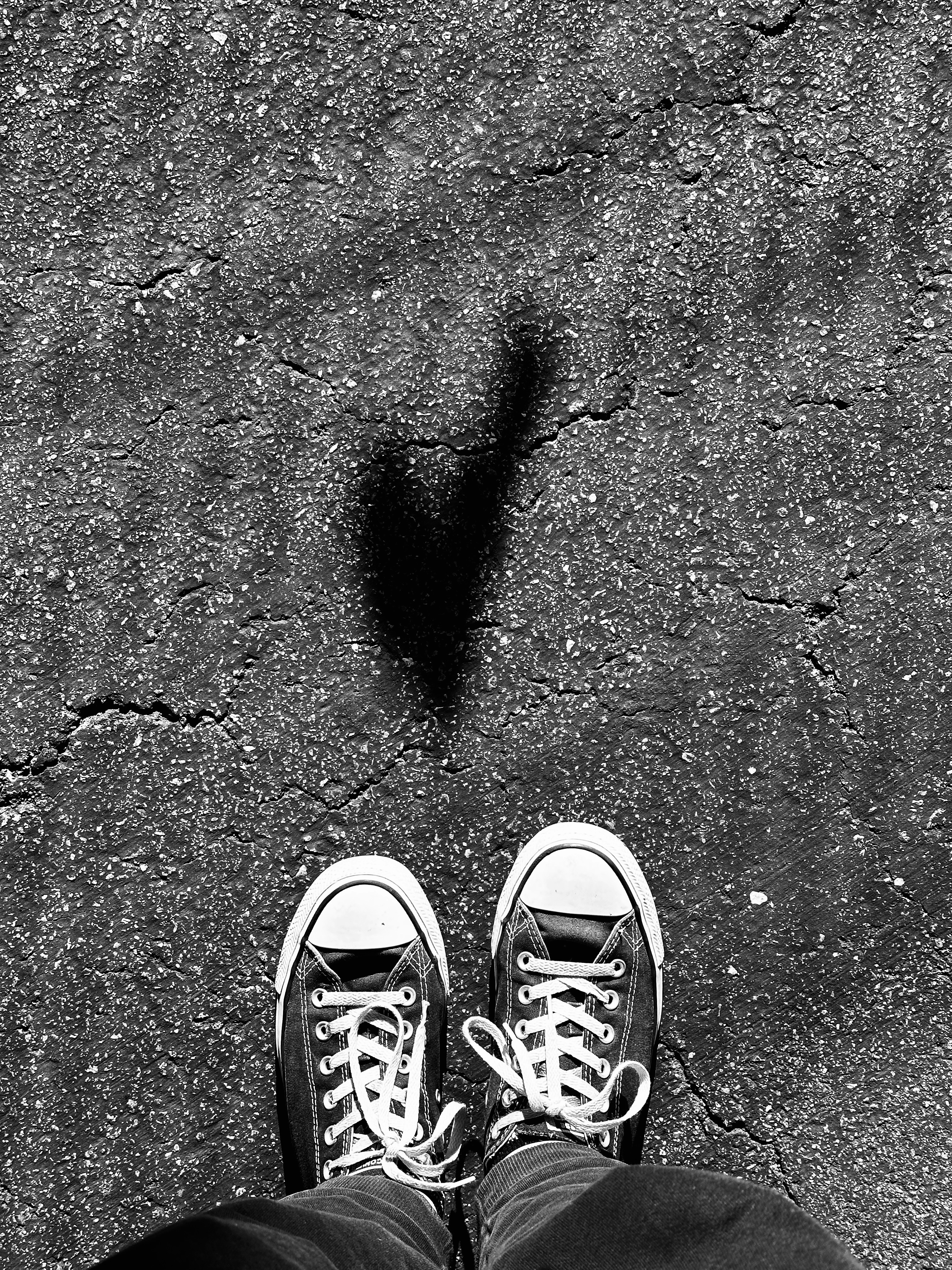 A person standing on a sidewalk with their feet up