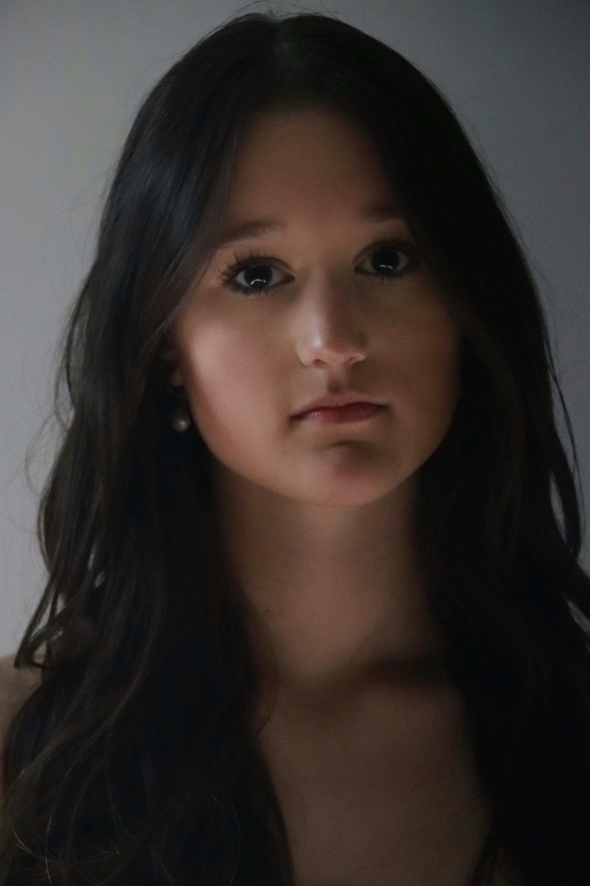 A woman with long black hair is looking at the camera