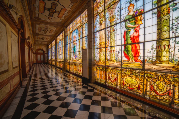A long hallway with a checkered floor and large stained glass windows