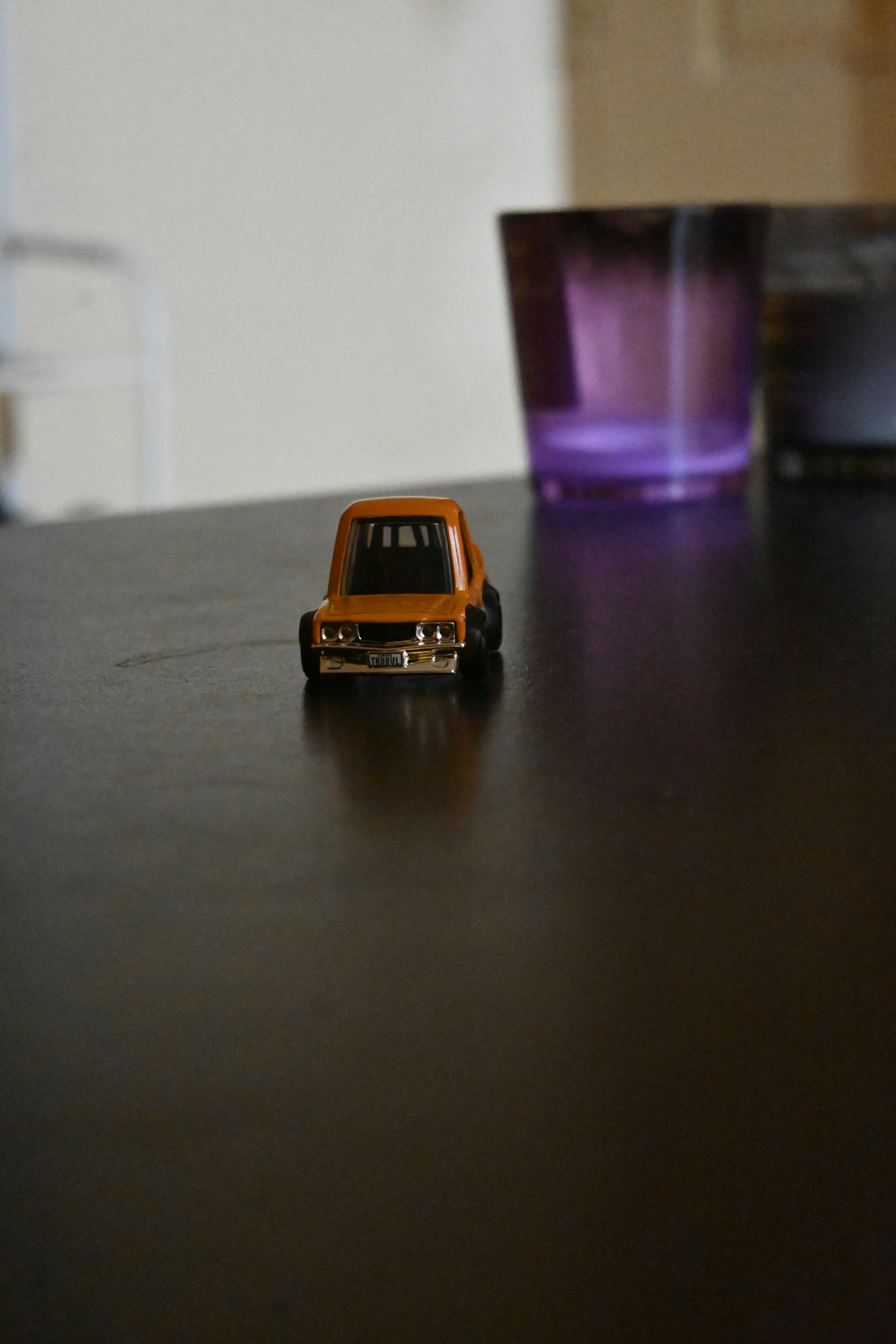 A toy car sitting on a table next to a glass