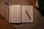An open book on a table with a pen and pencil