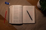 An open book on a table with a pen and pencil