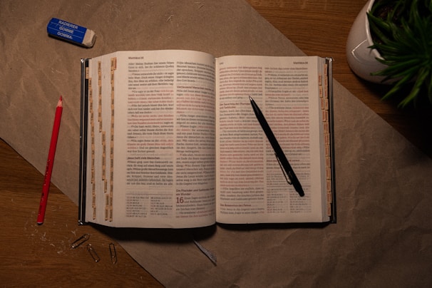 An open book on a table with a pen and pencil