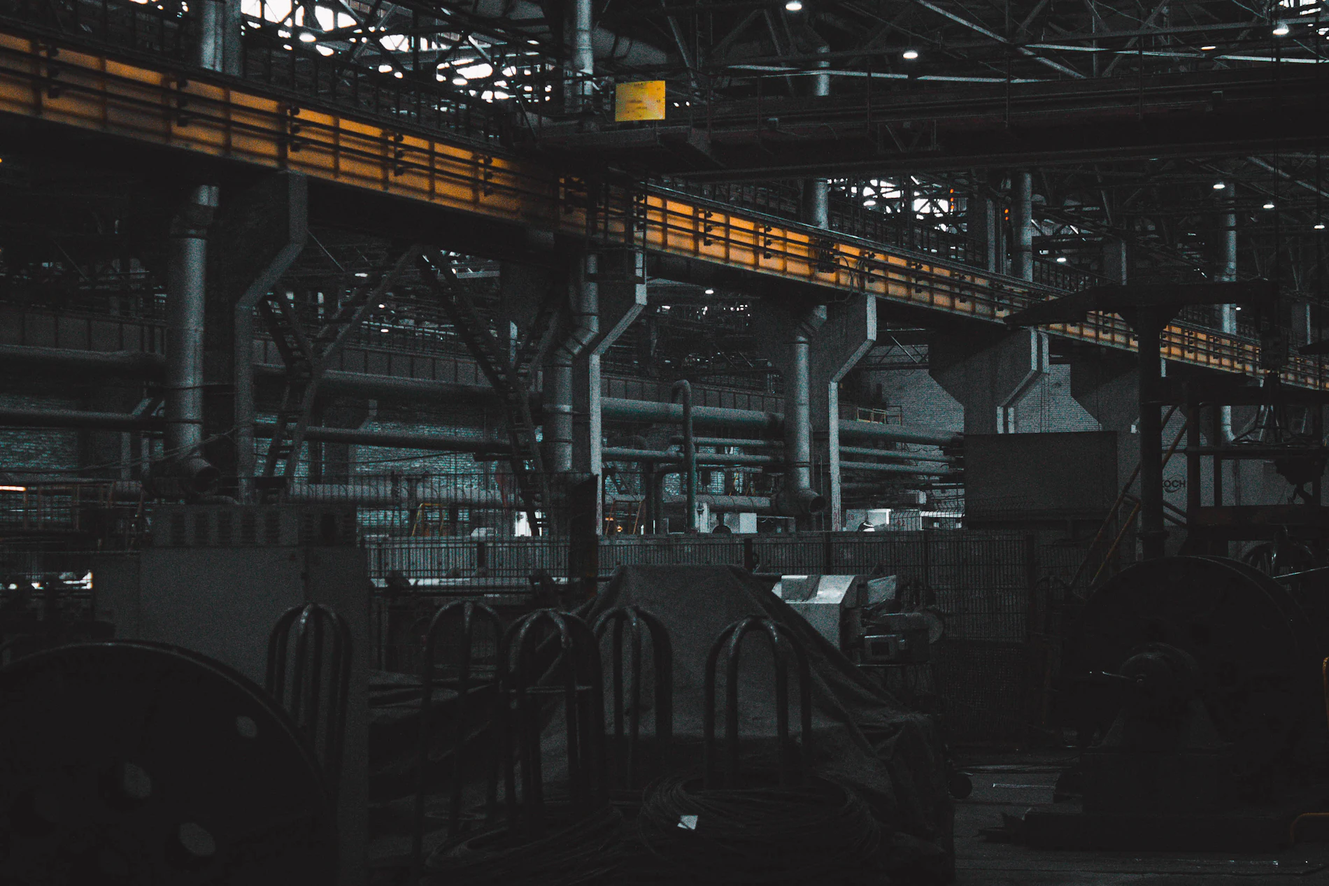 Interior de una planta industrial a oscuras, con el puente grúa cruzando la nave.