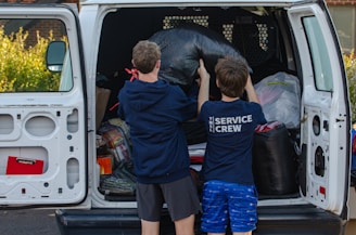 A couple of kids standing in the back of a van