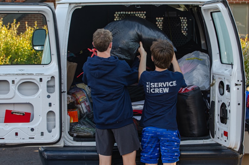A couple of kids standing in the back of a van