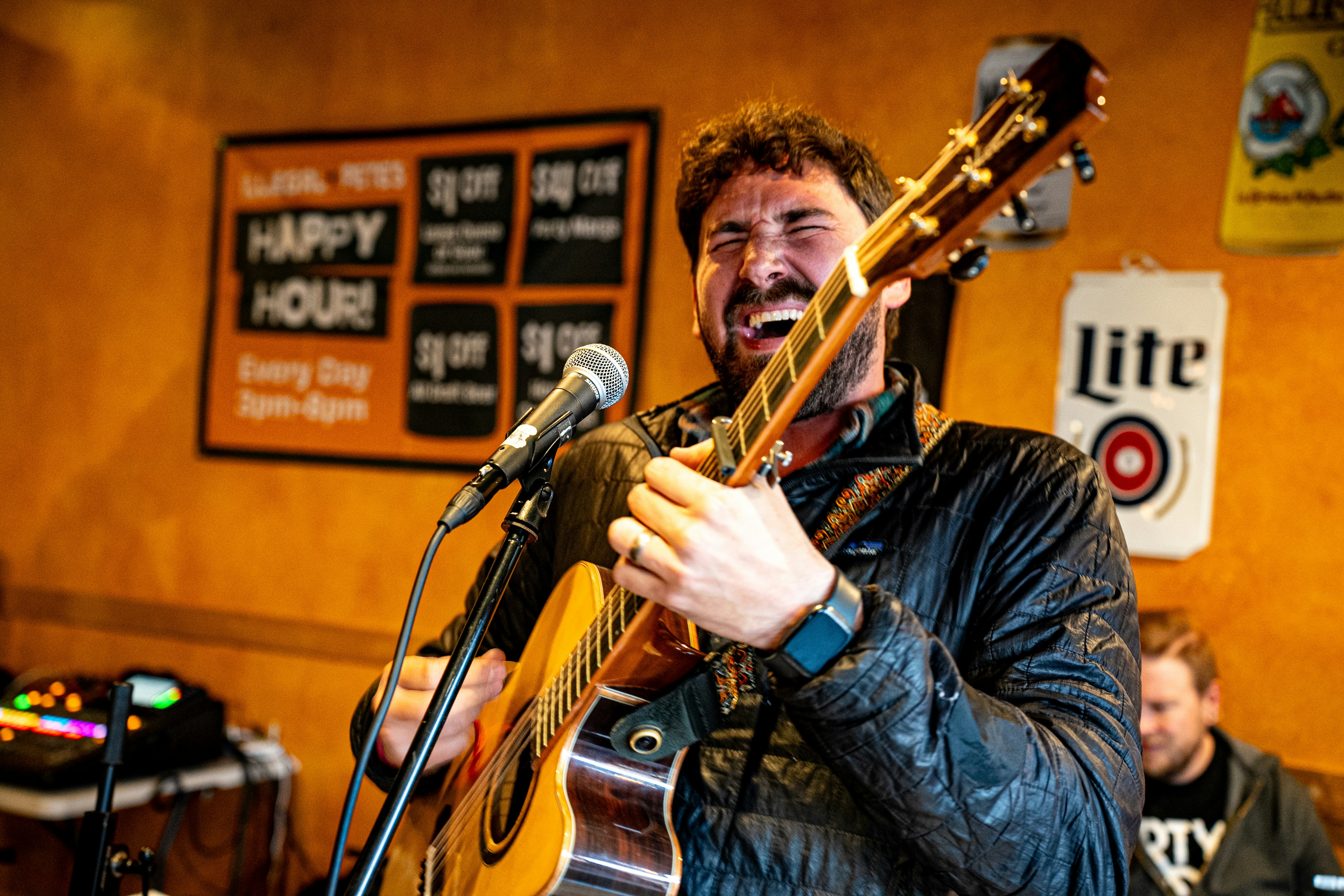 A man singing into a microphone while holding a guitar