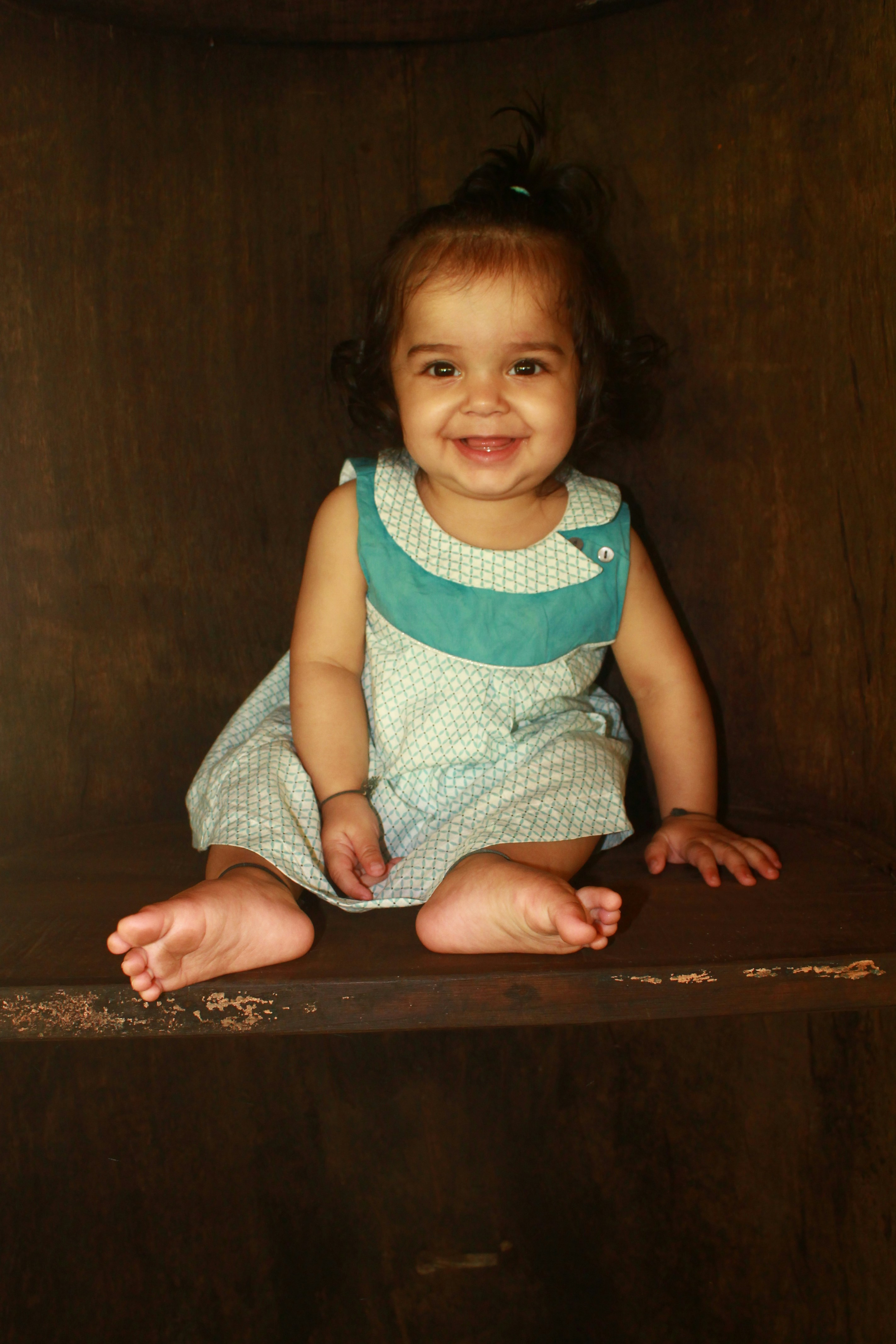 Ein kleines Mädchen sitzt auf einem Holzregal