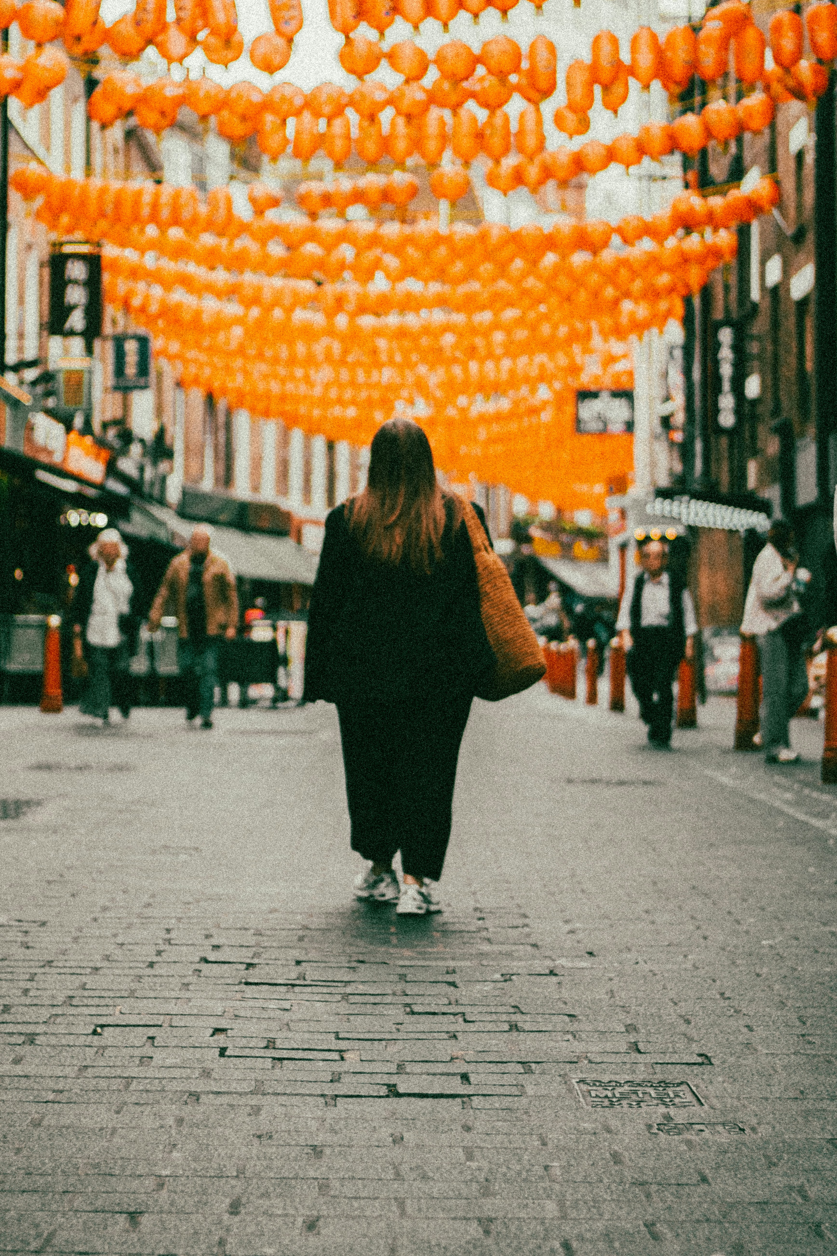 A woman walking down a street with orange decorations