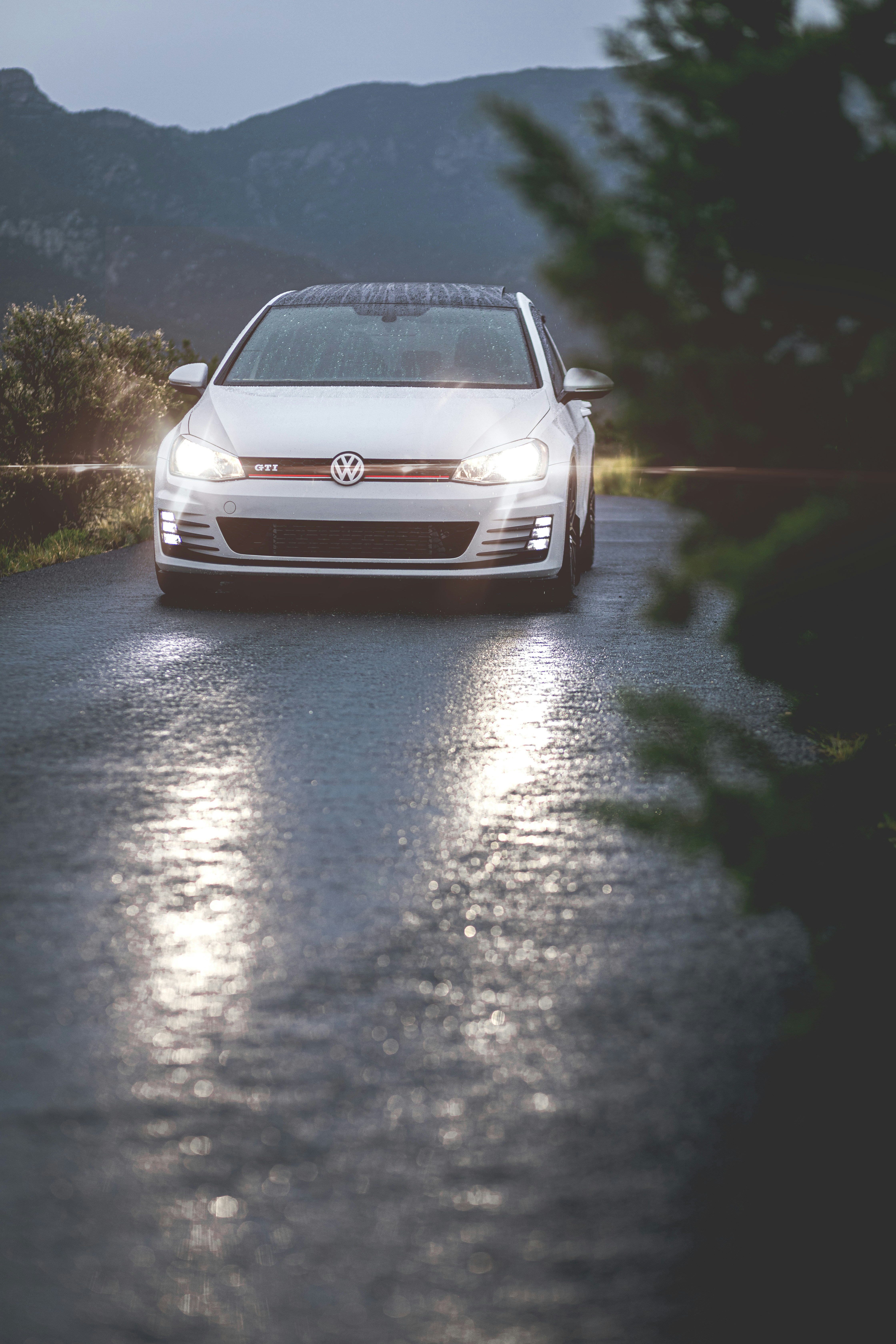 A white car driving down a wet road