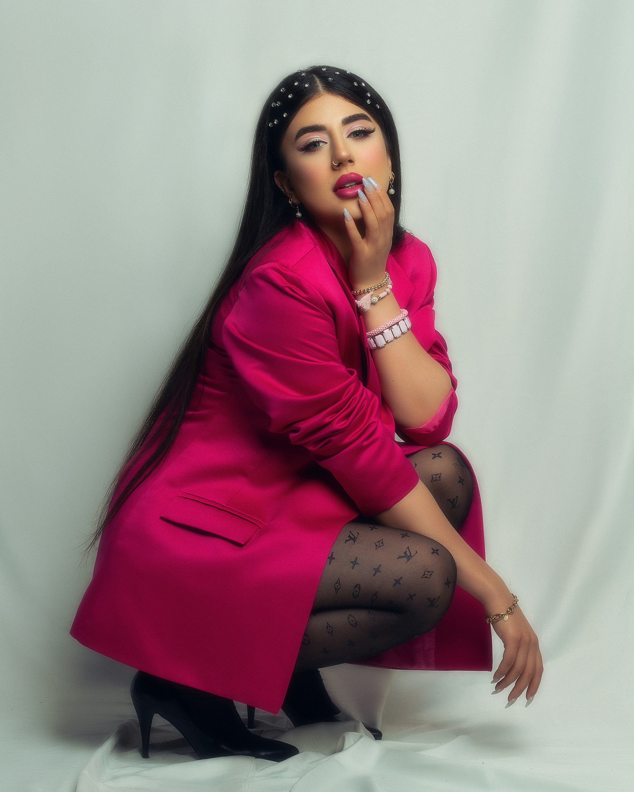Seorang wanita dengan mantel merah muda sedang berpose untuk berfoto