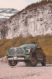 A green truck parked in front of a mountain
