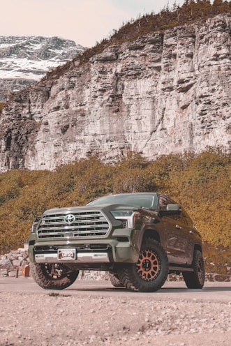 A green truck parked in front of a mountain
