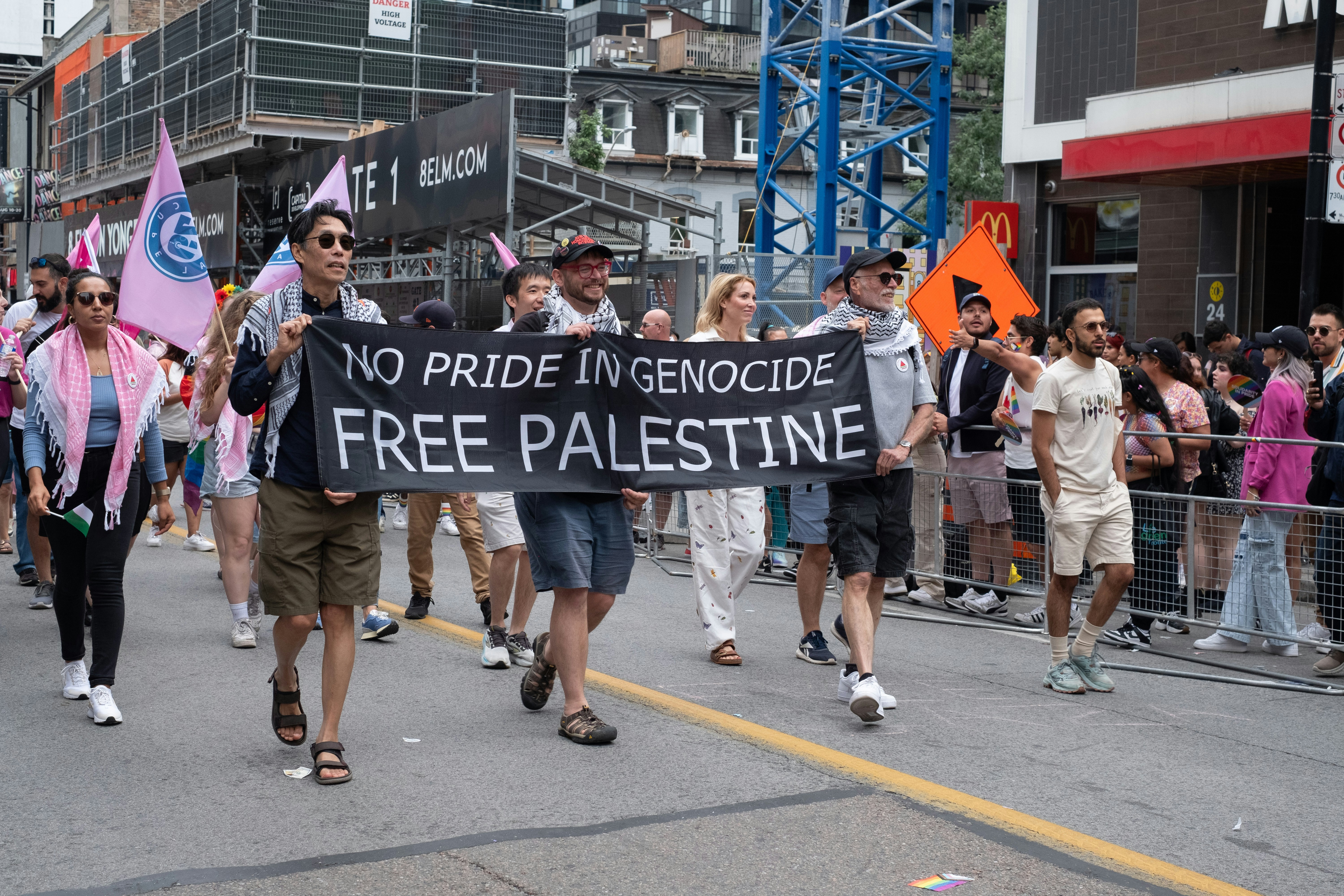 A group of people walking down a street holding a sign