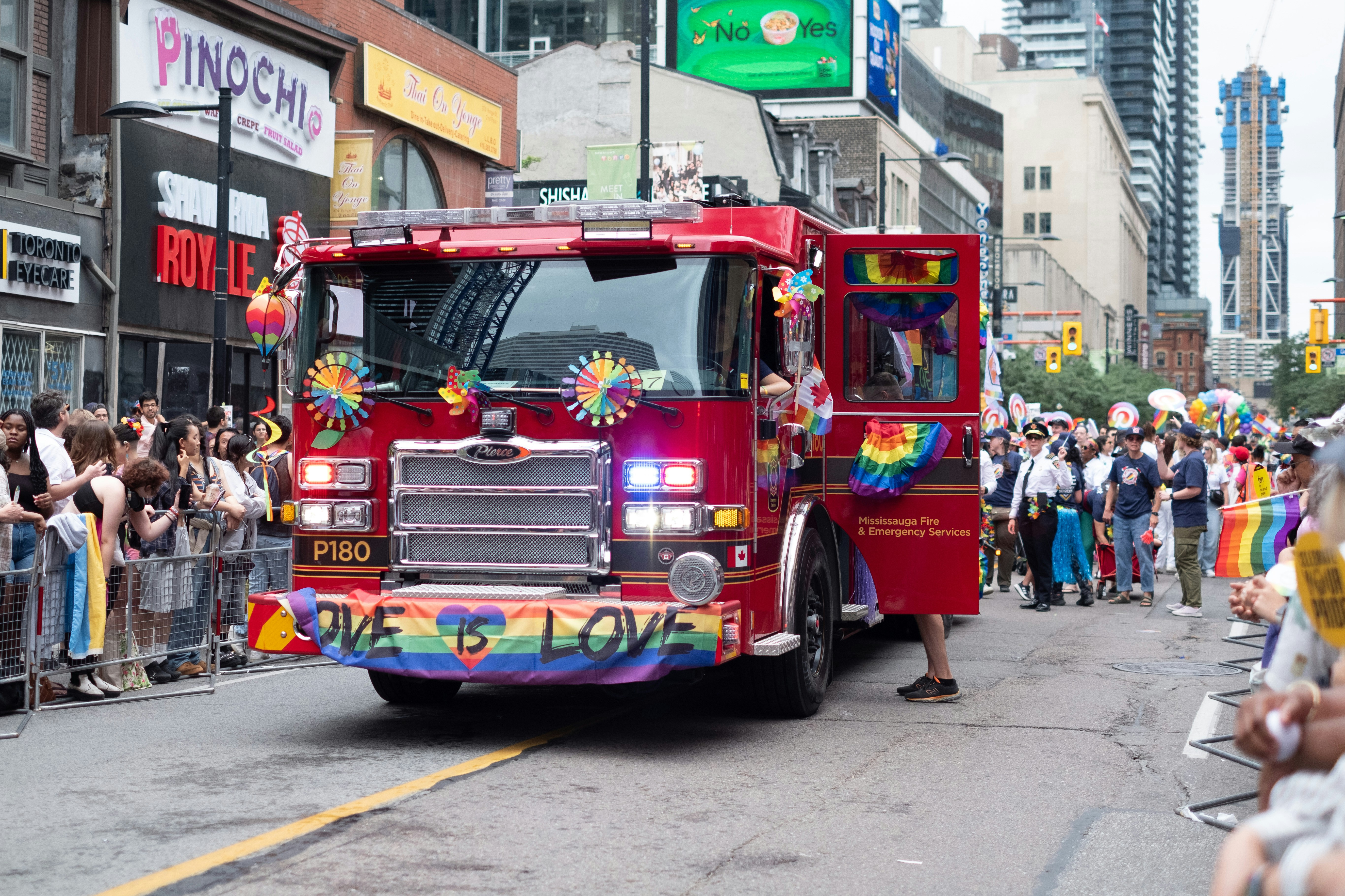 A red fire truck driving down a street next to a crowd of people
