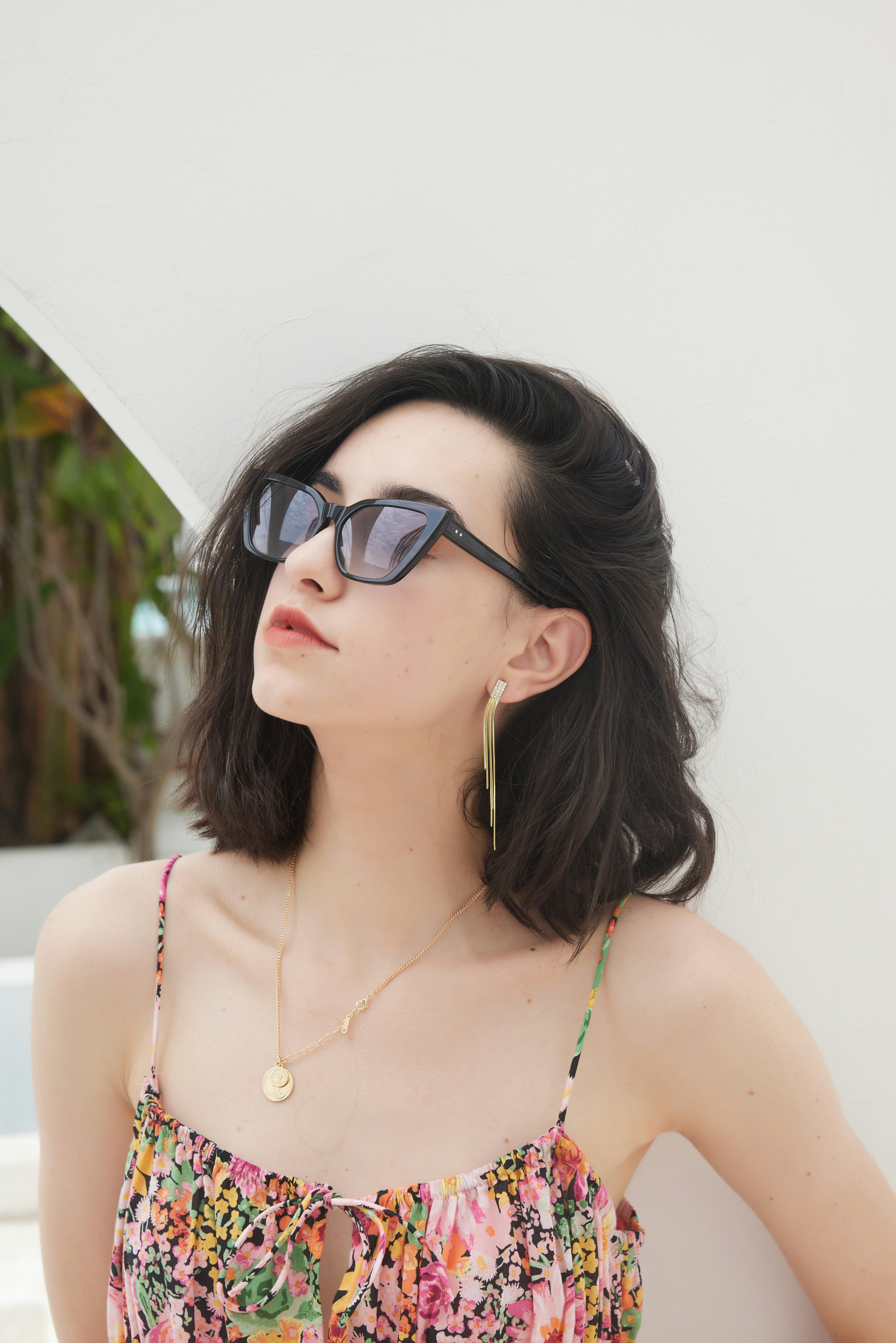 A woman wearing sunglasses leaning against a wall