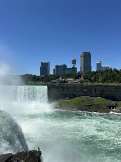 A large waterfall with a city in the background