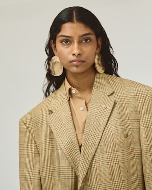 A woman wearing a tan suit and earrings