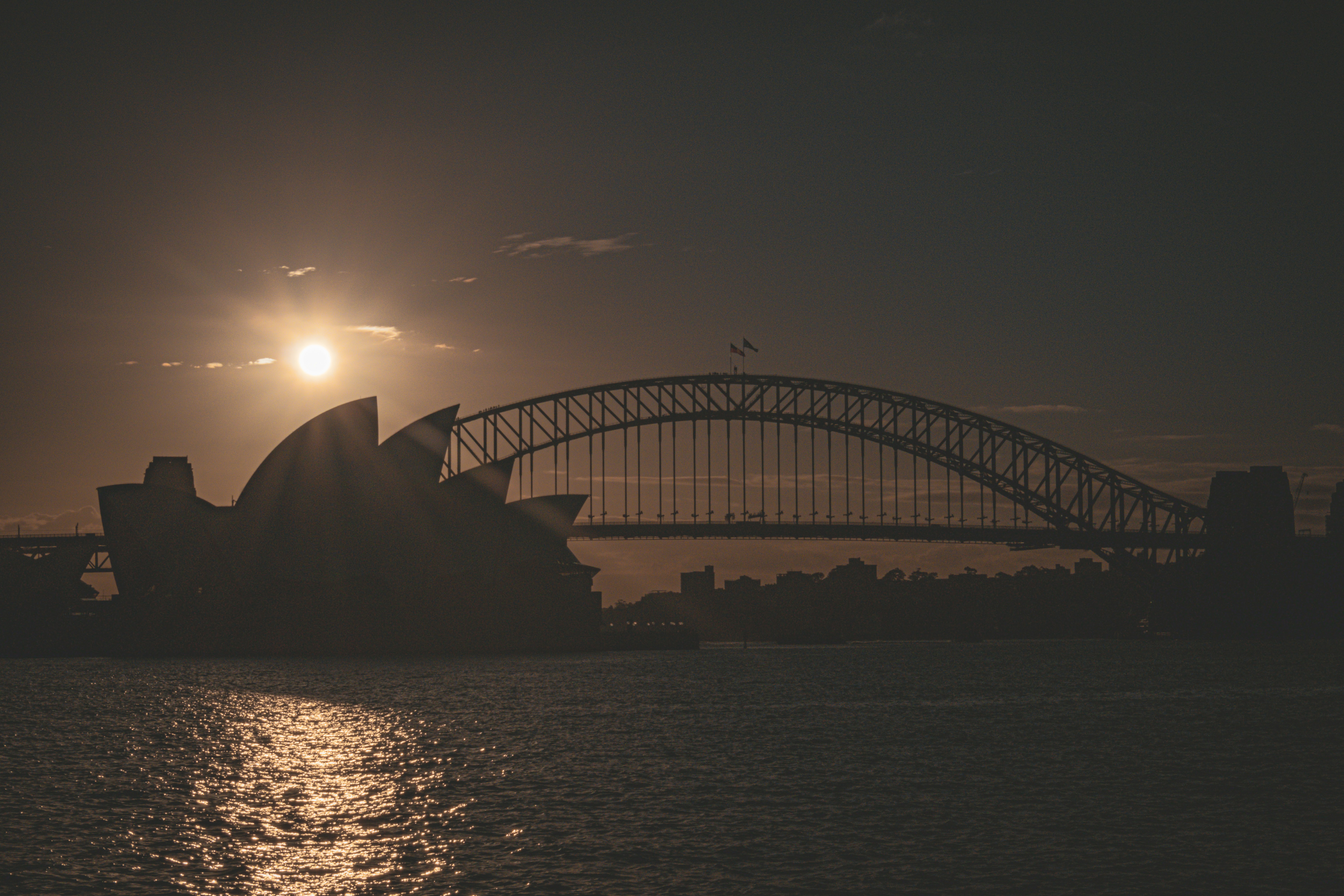 The sun is setting over the sydney opera house