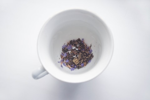 A white cup filled with purple flowers on top of a table