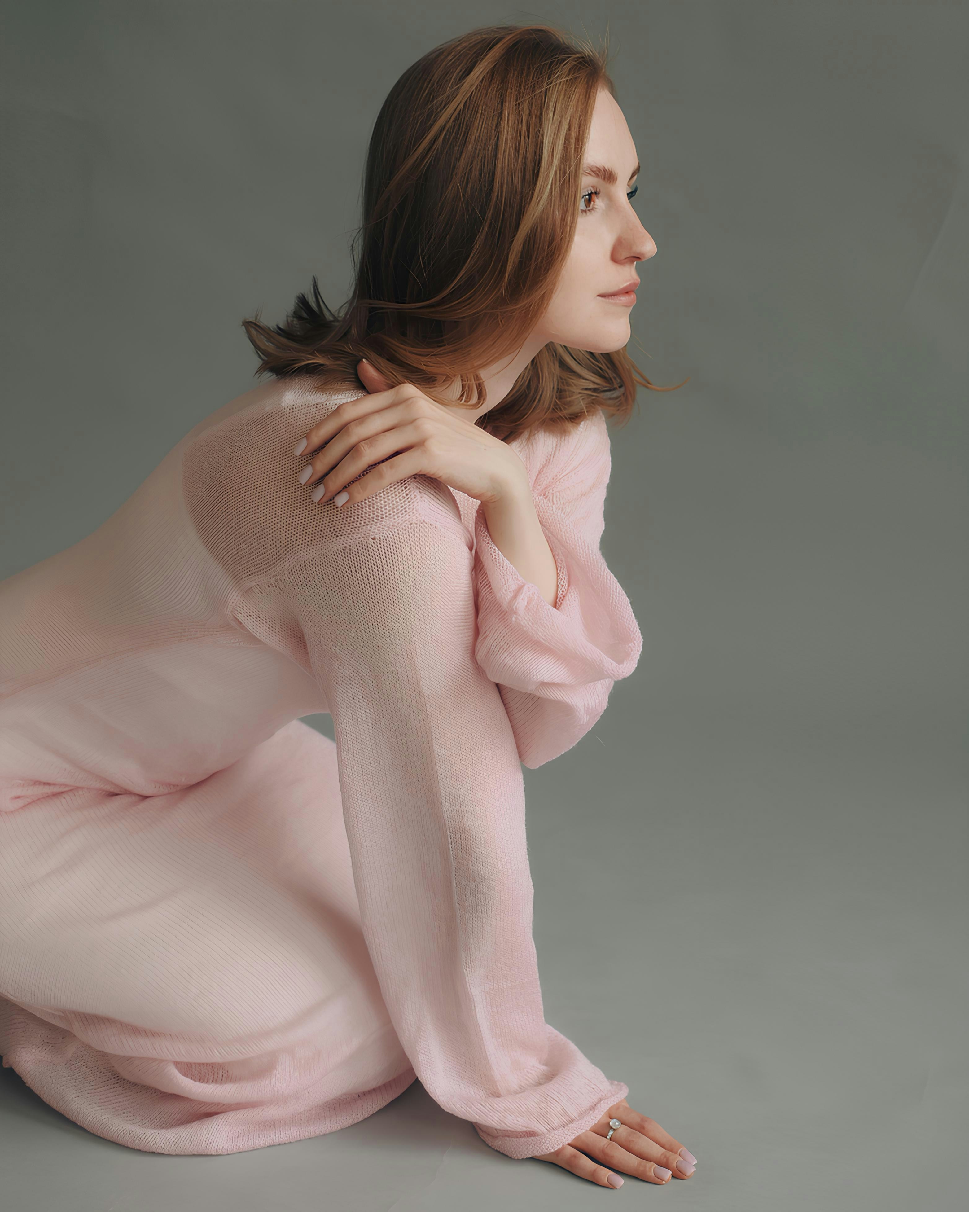 A woman in a pink dress sitting on the ground