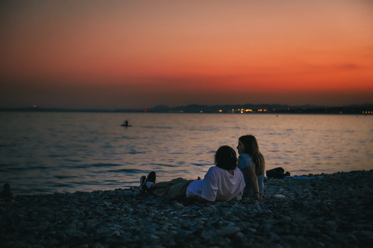 A couple of people sitting on top of a beach