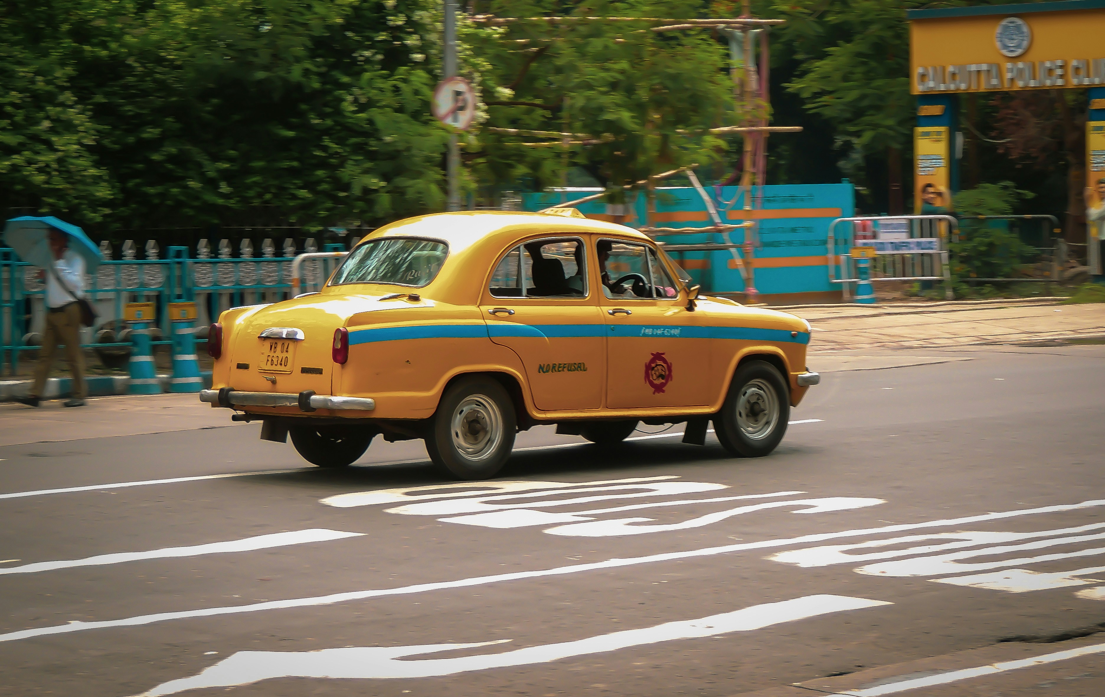A yellow and blue car driving down a street