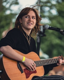 A woman playing a guitar in front of a microphone