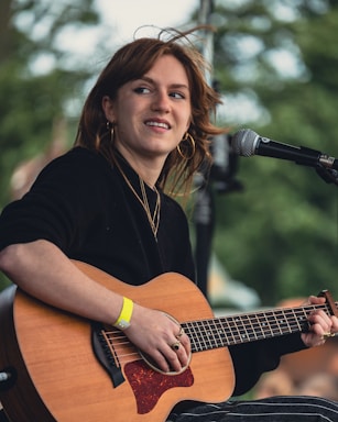A woman playing a guitar in front of a microphone