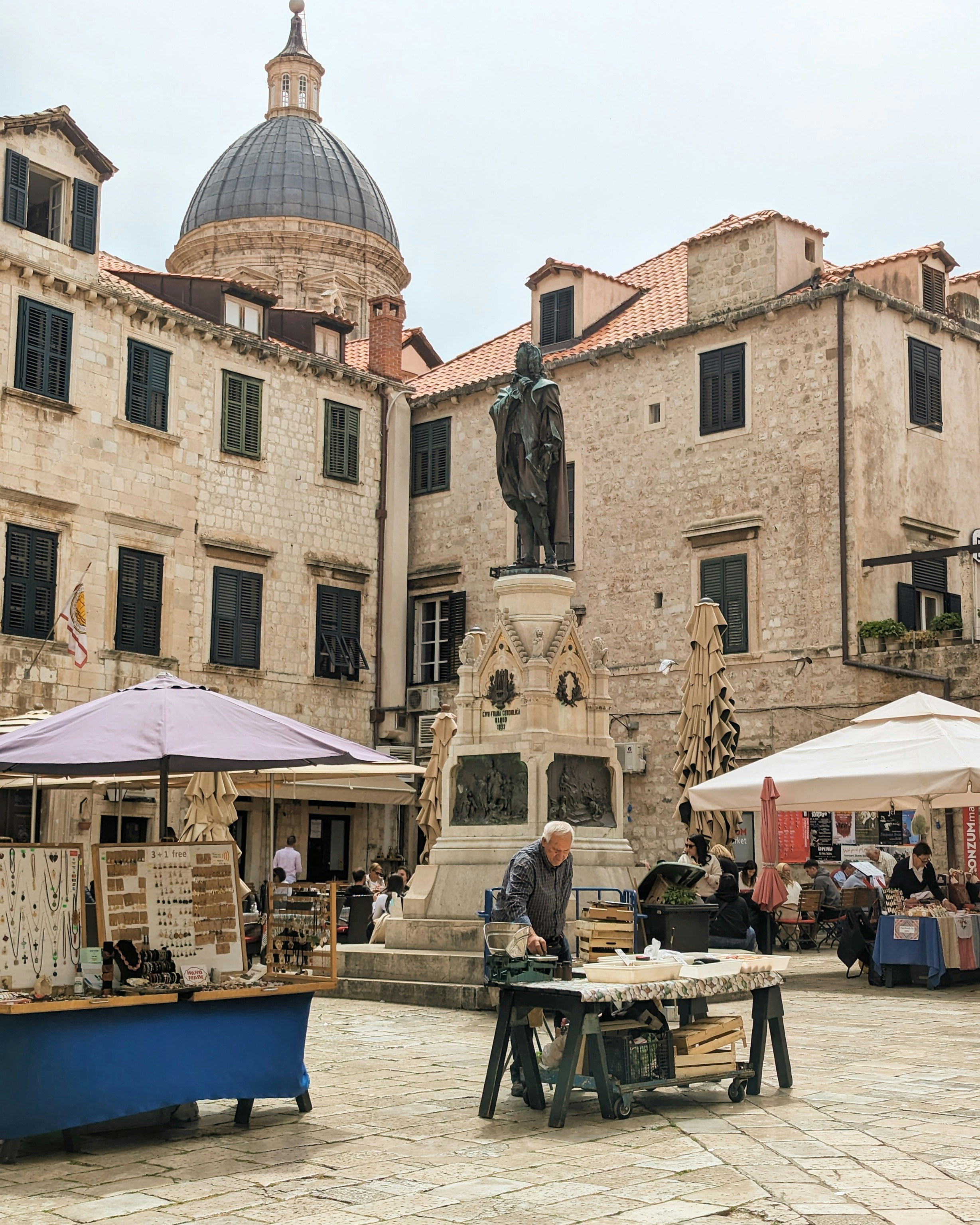An outdoor market with tables and umbrellas in front of a building