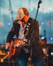 A man with a hat playing a guitar
