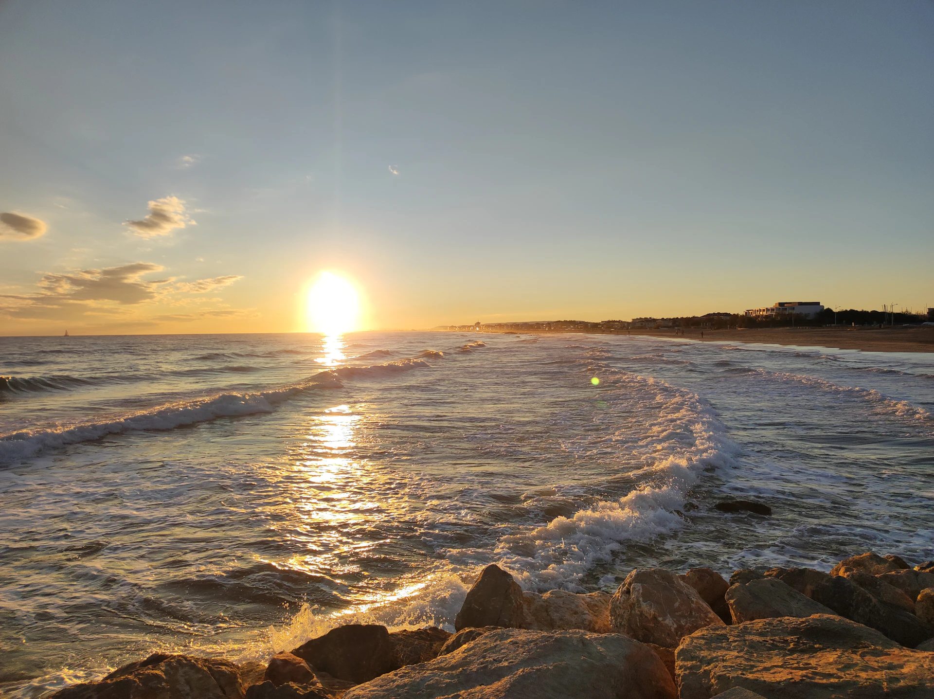 The sun is setting over the water at the beach