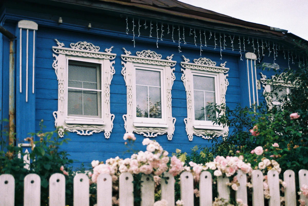 Blue house with white trim and a white picket fence