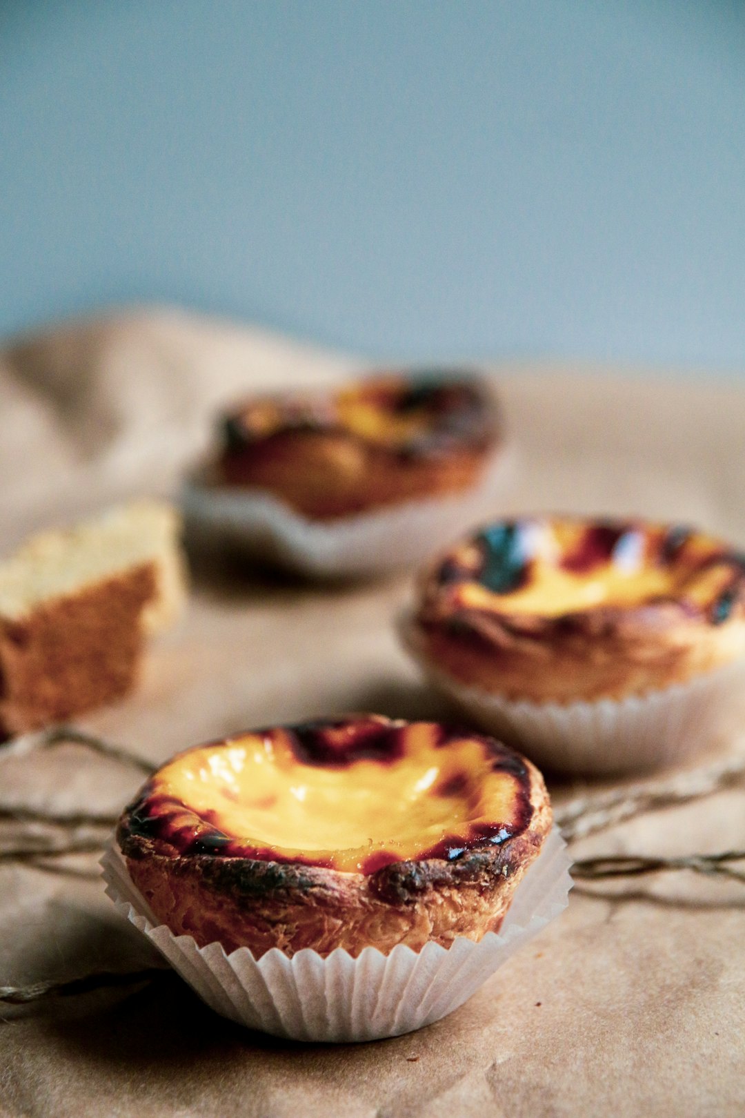 A table topped with three pastry cups covered in cheese