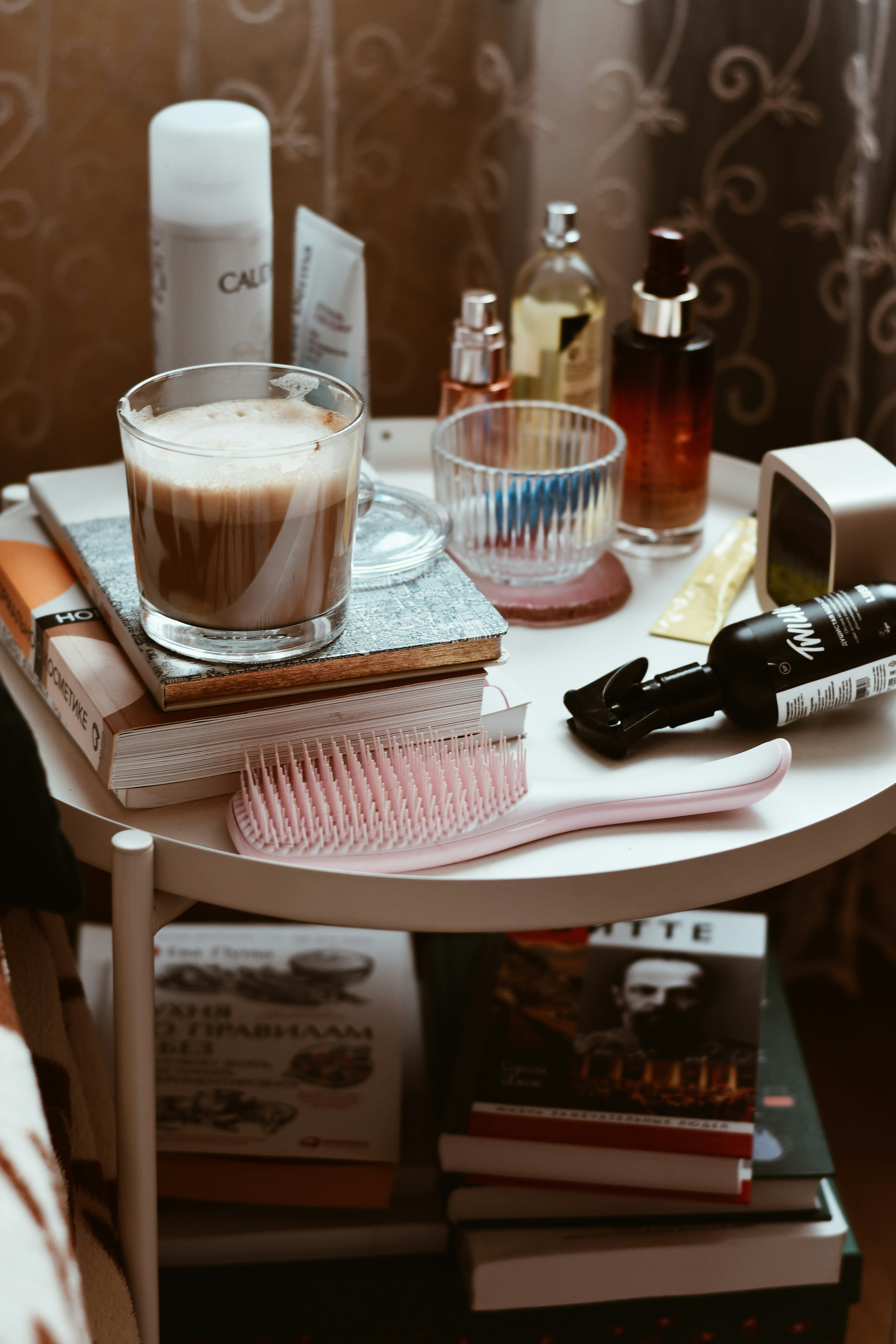 A white table topped with books and a cup of liquid