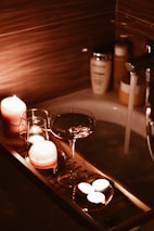 A bath tub filled with candles and a wine glass