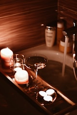 A bath tub filled with candles and a wine glass